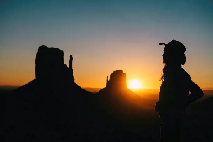 USA, Utah, Monument Valley, silhouette of woman with cowboy hat watching sunrise