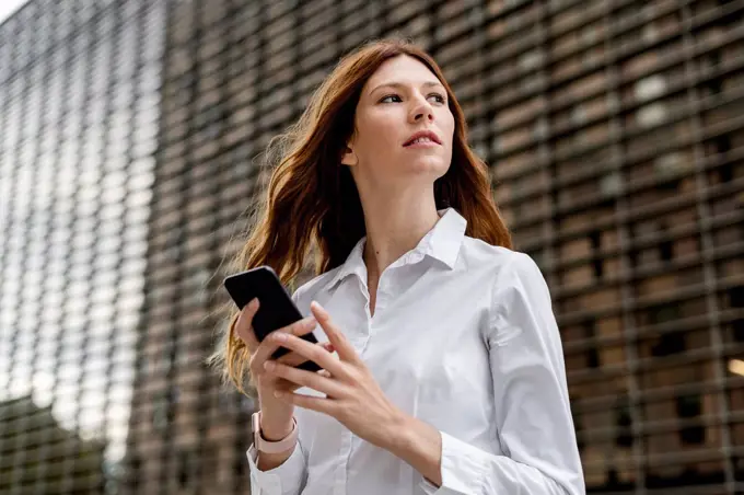 Young businesswoman in the city, using smartphone