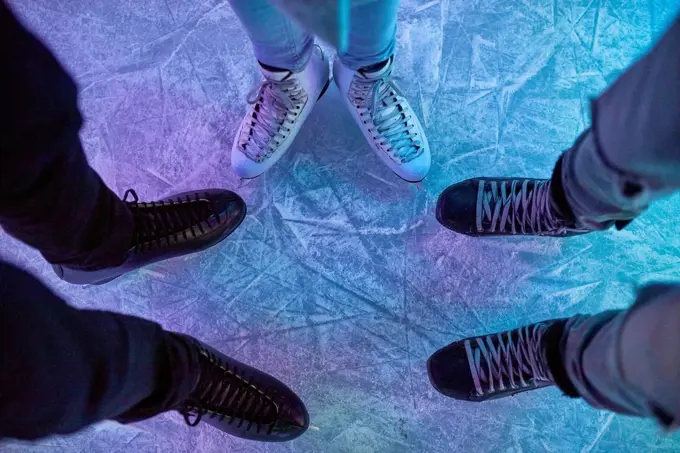 Legs of friends wearing ice skates standing on an ice rink