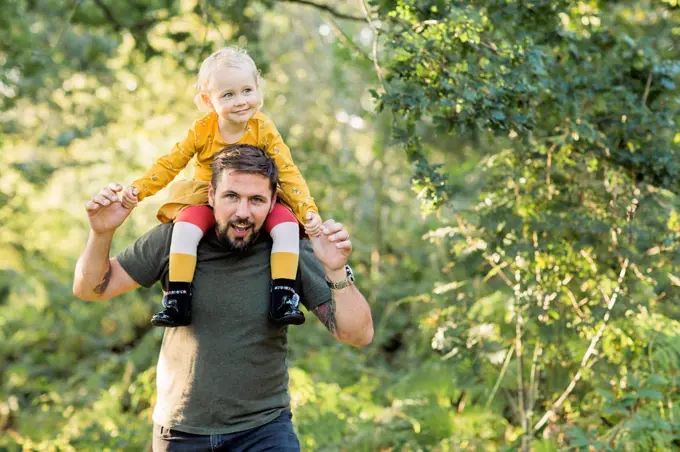 Mature man playing with his little daughter in nature