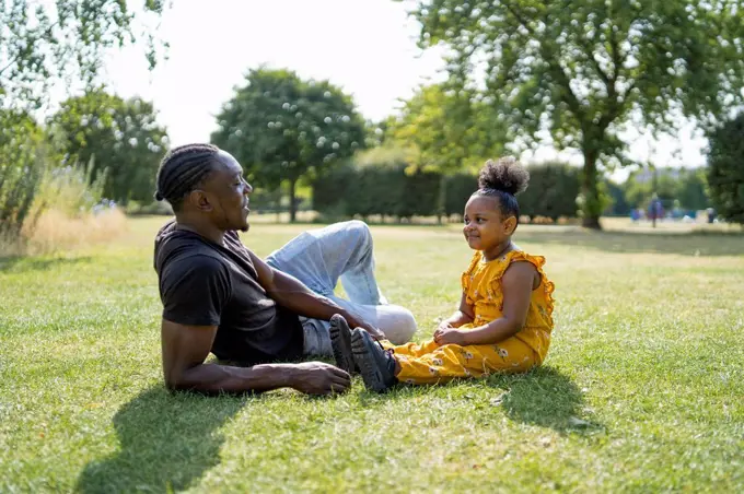 Father and daughter relaxing on a meadow in a park