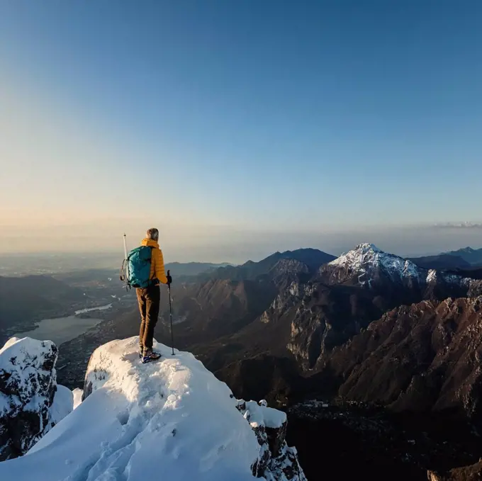 Mountaineer standing on top of a snowy mountain enjoying the view, Lecco, Italy