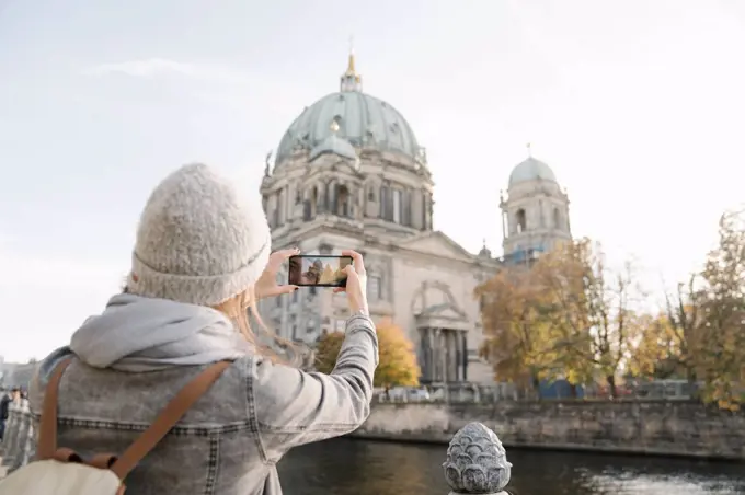 Young woman taking a smartphone picture of Berlin Cathedral, Berlin, Germany