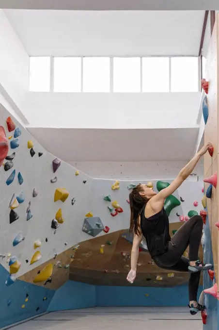 Woman bouldering in climbing gym