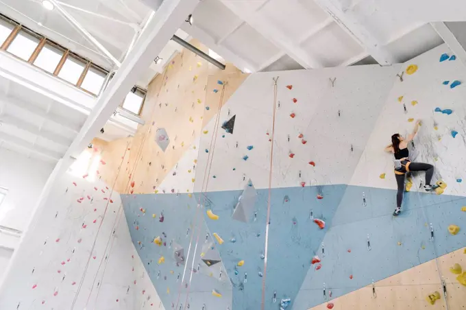 Woman climbing on the wall in climbing gym