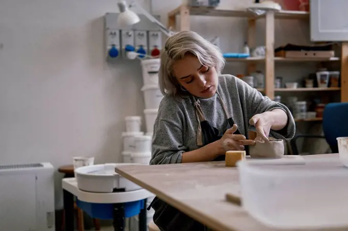 Young woman working on workpiece in pottery