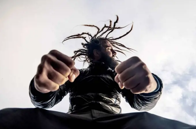 Bearded man with dreadlocks clenching fists
