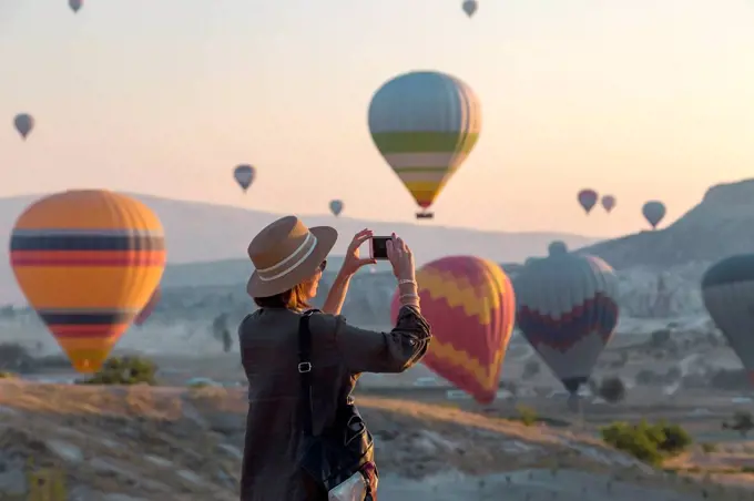Young woman and hot air ballons, Goreme, Cappadocia, Turkey