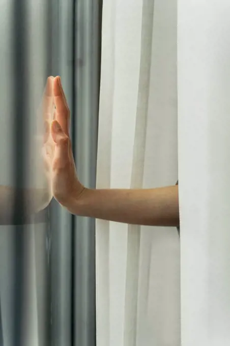 Hand of a woman touching windowpane
