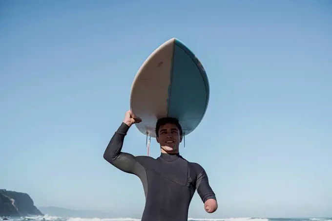 Handicapped surfer carrying his surfboard on head