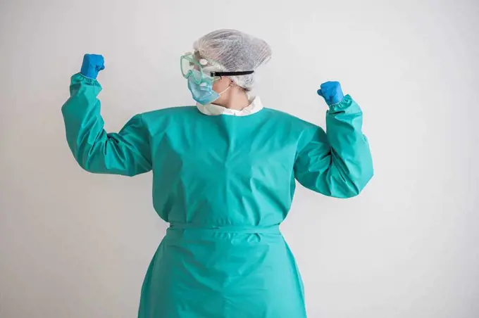 Woman wearing personal protective equipment flexing her muscles