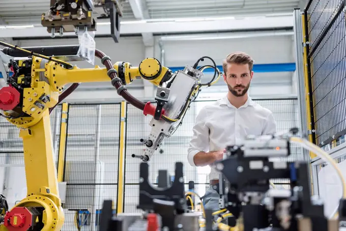 Confident male robotics expert looking at machinery in automated industry
