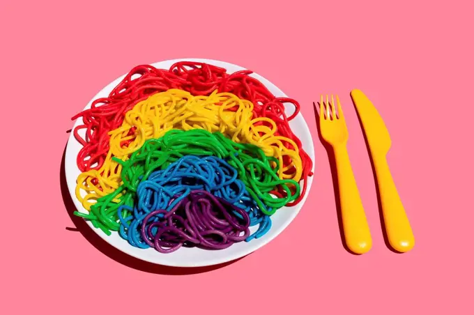 Plate of rainbow-colored¶ÿspaghetti against pink background