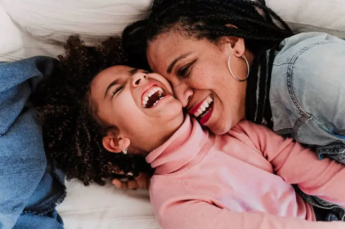 Portrait of laughing little girl and her mother having fun together at home