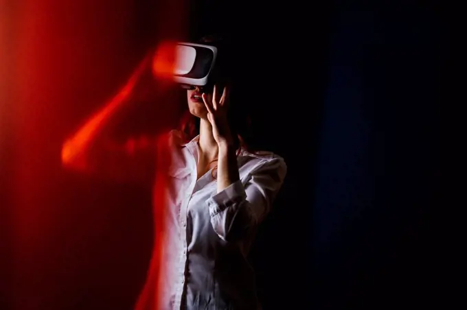 Young woman using VR glasses over black background