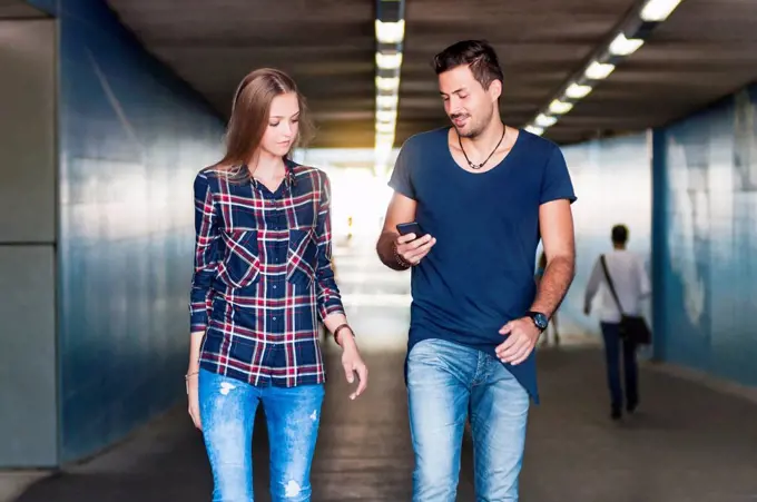 Young man and young woman walking together in an underpass