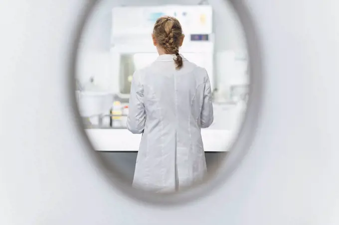 Senior female scientist seen through window at laboratory, rear view