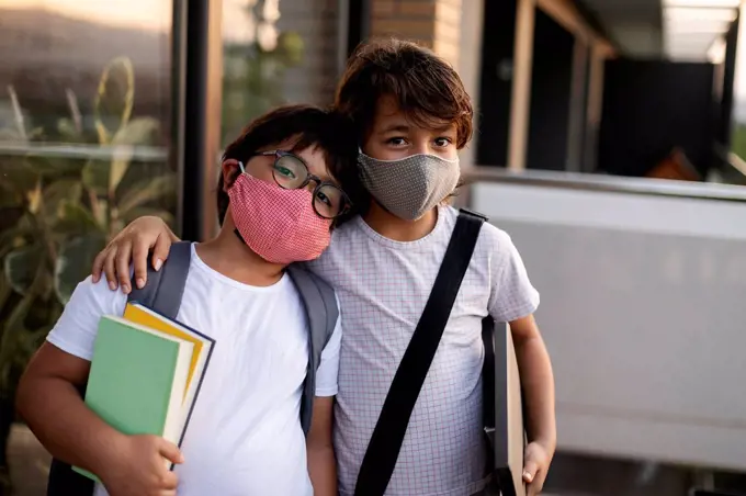 Siblings with books wearing masks outdoors
