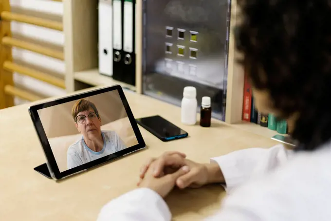 Senior woman on digital tablet screen during video call with doctor