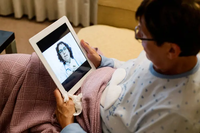 Doctor discussing illness with senior woman through video call