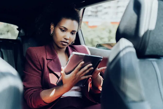 Young female entrepreneur using digital tablet while sitting in car
