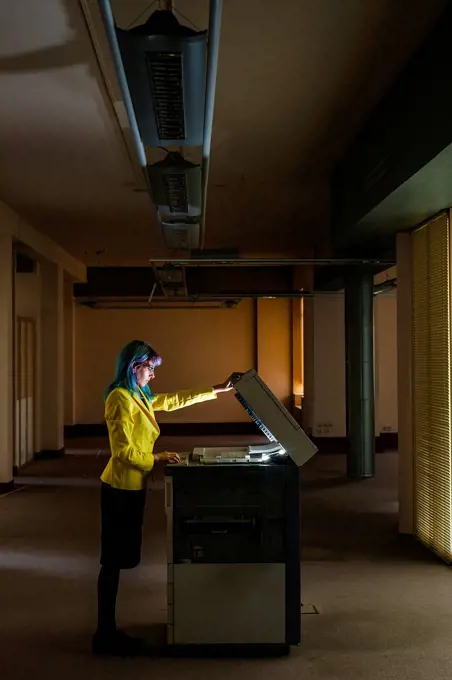 Businesswoman with dyed hair operating photocopier in old abandoned office