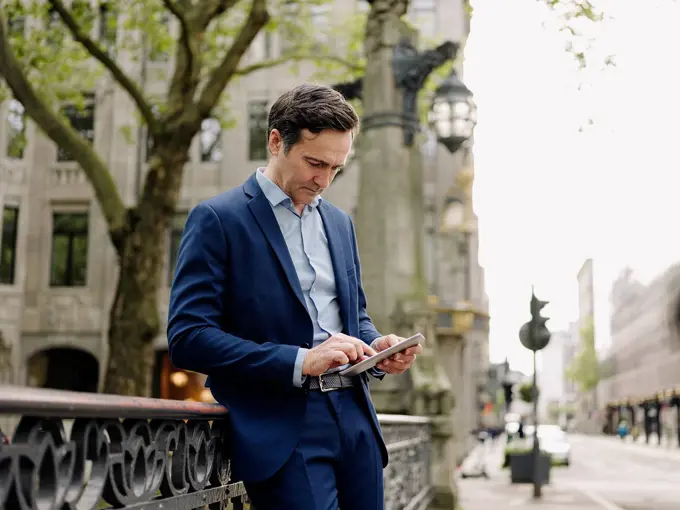 Mature businessman using tablet on a bridge in the city