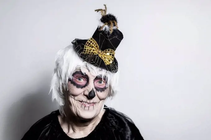Portrait of senior woman with sugar skull make-up and fancy hat