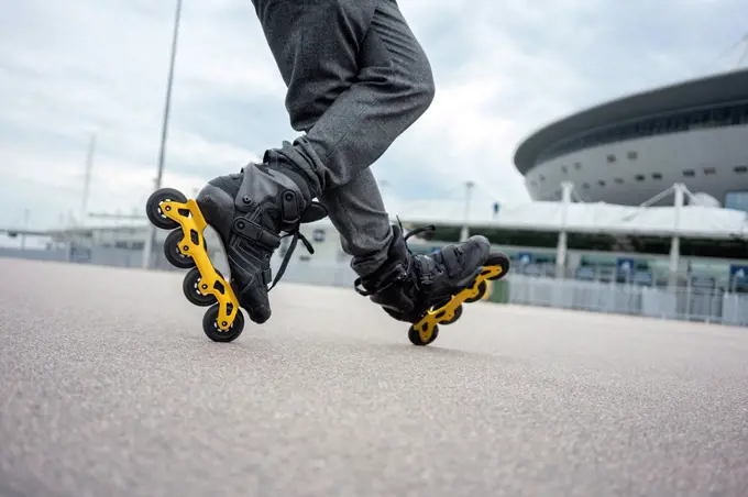 Legs of young man inline skating on road against sky