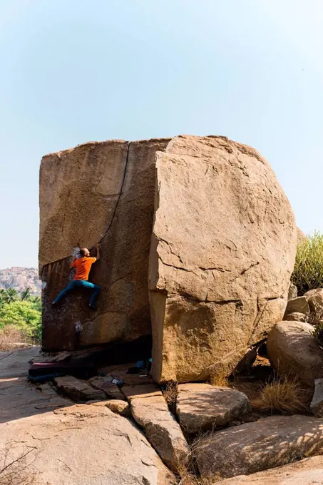 Male rock climber ascending huge boulder