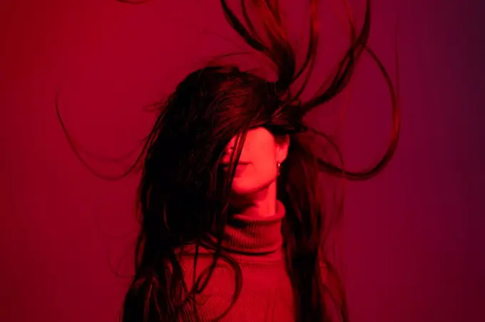 Woman tossing hair against red background
