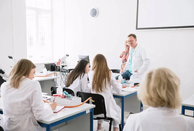 Students having lecture with professor in science lab classroom