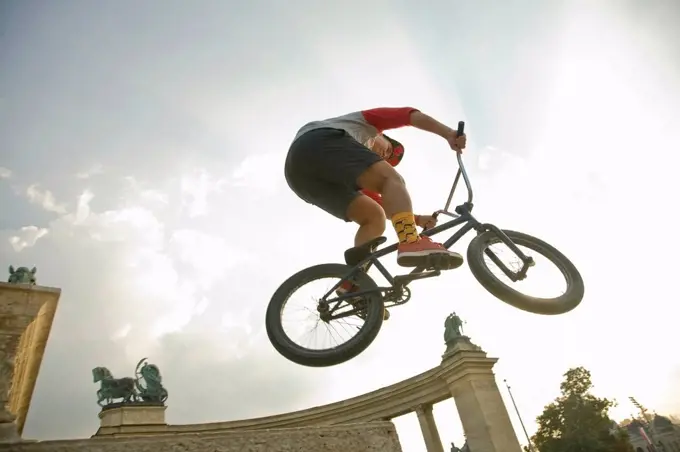Young man performing stunt on BMX bicycle at Hero's Square, Budapest, Hungary
