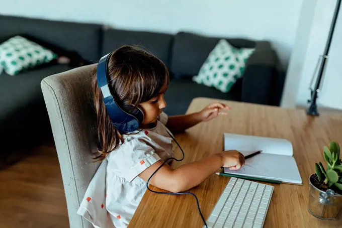 Female preschooler wearing headphones at desk