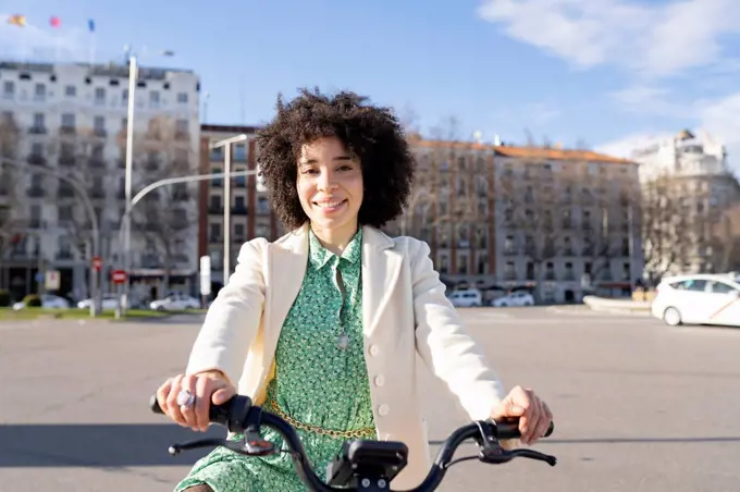 Afro young woman with electric bicycle in city