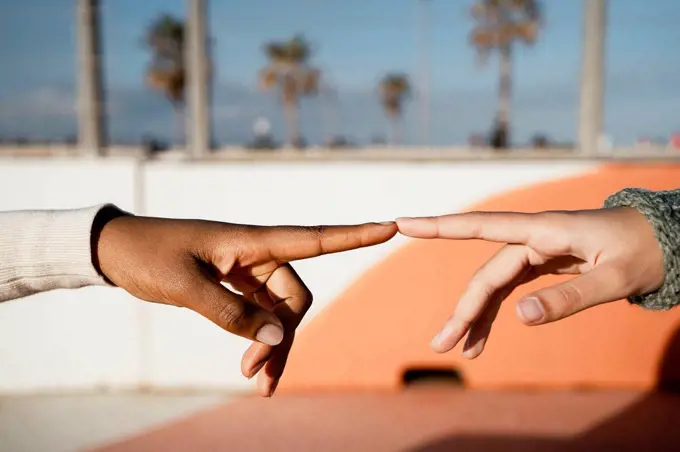 Close-up of friends index finger pointing each other outdoors