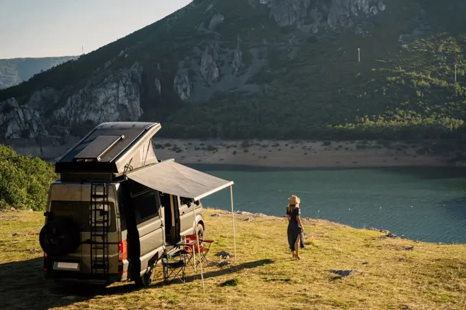 Woman looking at lake while standing by camper van during vacation