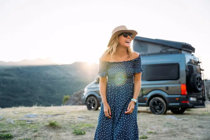 Laughing woman looking away against motor home on sunny day