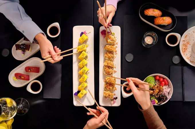 Female customers eating fresh sushi with chopsticks at restaurant