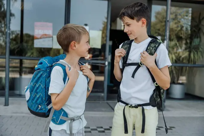 Brothers looking at each other while standing in front of school building