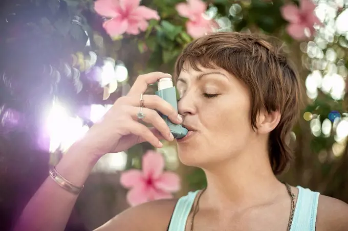 Young woman breathing through asthma inhaler