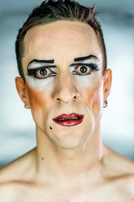 Close-up portrait of drag queen with make-up against gray background
