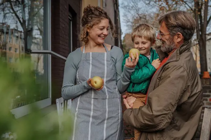 Smiling saleswoman selling apple to father and son at retail store