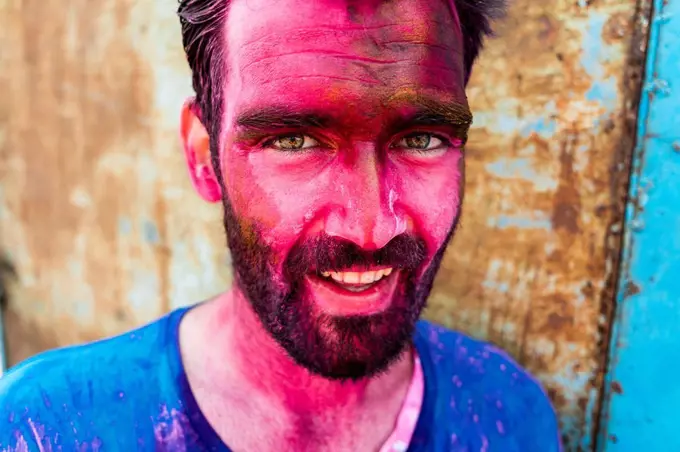 Close-up of smiling bearded man with pink face during Holi festival