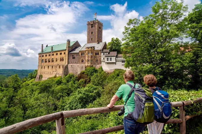 Tourists watching Wartburg Castle while standing by wooden railing in Eisenach, Germany