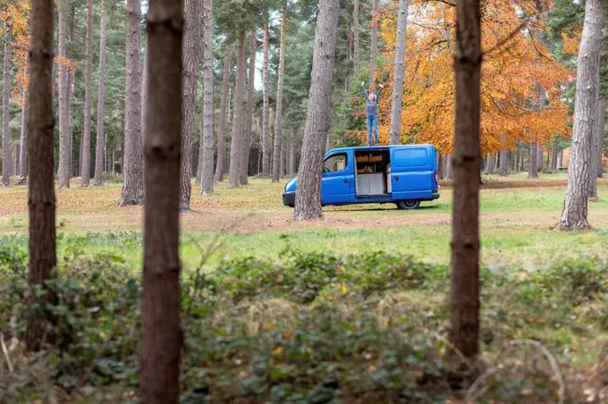 Woman with hand raised standing on top of motor home at Cannock Chase