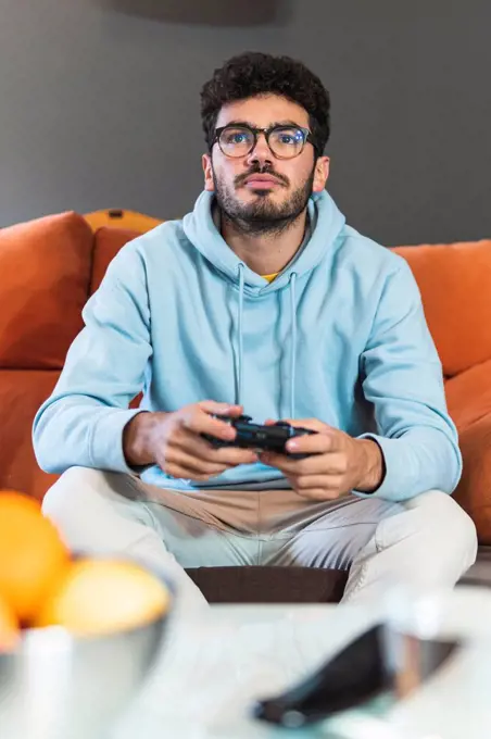 Concentrated young man playing video game in living room