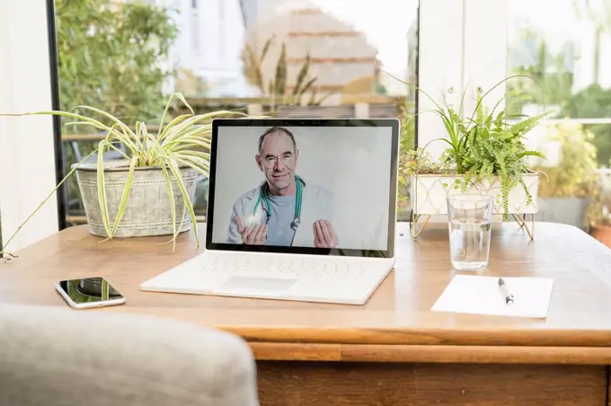 Smiling doctor on video call through laptop at home