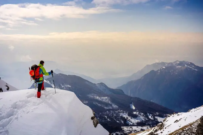Male alpinist admiring view while standing on snowcapped mountain