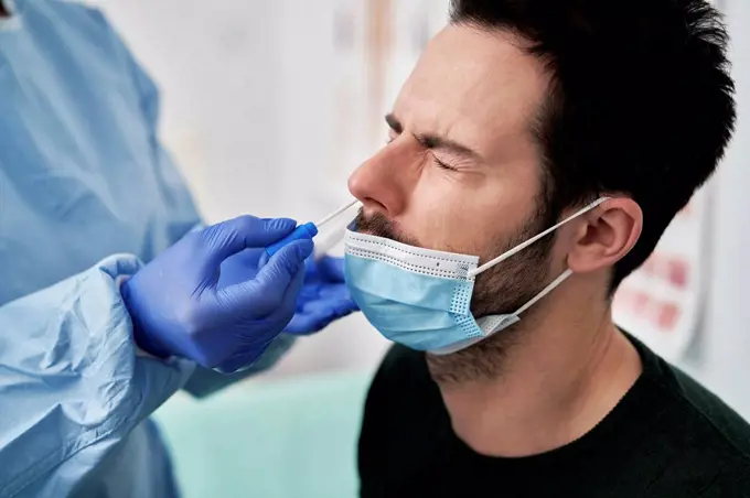 Medical professional collecting sample using nasal swab for COVID-19 test